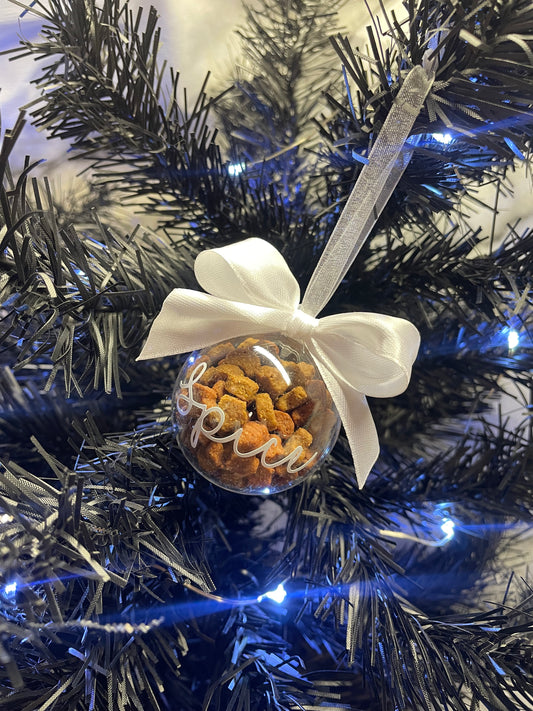 Christmas bauble filled with cat treats. White ribbon and the name spice on the front